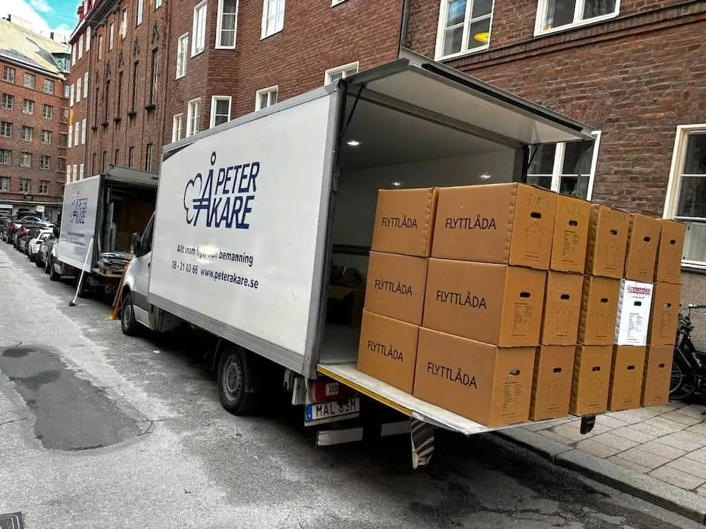 Flyttbil från Peter Åkare lastad med bruna flyttlådor på stadsgata.